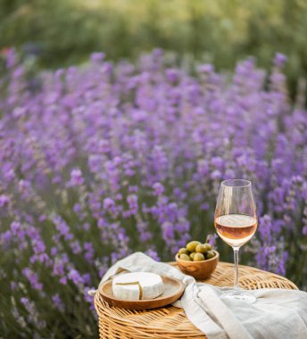 Lavanta tarlasında bir bardak beyaz şarap. Arka planda mor çiçekler