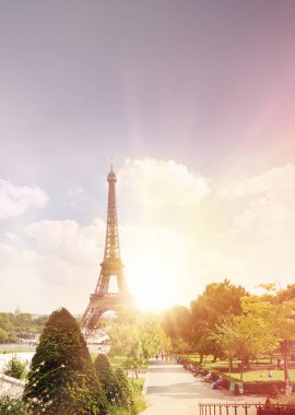 Günbatımı ışınlı yeşil yaz ağaçlarının arasından Eyfel Kulesi 'ni seyret. Güzel romantik bir geçmişi var. Champ de Mars 'tan Eyfel Kulesi, Paris, Fransa.