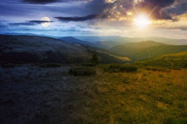 Yazın alacakaranlıkta Carpathian sıradağları. Gündüz ve gece zaman kavramını değiştirir. Orman tepeleri ve çimenli çayırları olan manzara güneşli ve aylı bir gökyüzünün altındaki vadiye doğru iniyor.