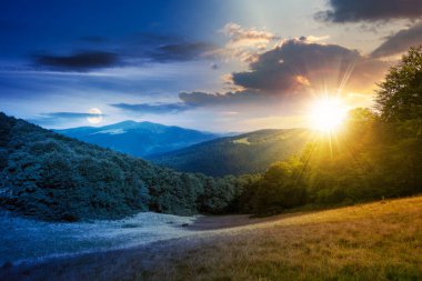 green pasture on the hillside at twilight. day and night time change concept. forested mountains in the distance. beautiful countryside landscape of transcarpathia in summer with sun and moon