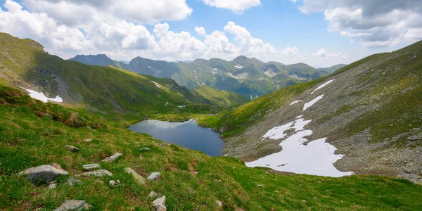 stock image high altitude mountain lake. beautiful nature landscape of romania. grass and snow on the hills. sunny weather with clouds on the sky in summer