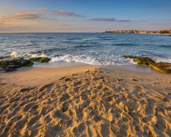 black sea shore at sunrise. vacation and leisure background. landscape with rock on the sand and town in the distance on the horizon line on a sunny morning