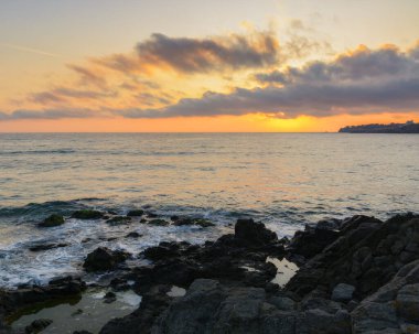 dramatic sunrise at the sea. rocky coast and cloudy sky