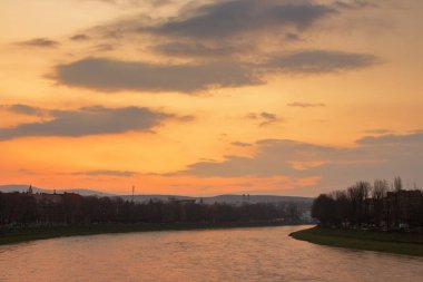 uzhhorod cityscape at dawn. linden alley on the embankment. gorgeous cloudscape above the river