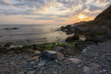 pebble sea shore with rocks at dawn. beautiful view of bulgaria seascape on a cloudy morning