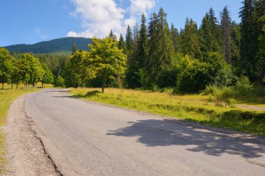 Yeşil tepeler ve görkemli dağlarla çevrili huzurlu bir manzara. Kırsal arazide uzanan yollar huzurlu bir sabah manzarası sunuyor.