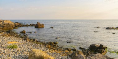 Gün doğumunda çakıl taşı sahili. Denizde yaz tatili sezonu