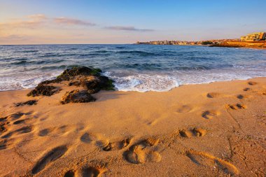 Denizde gün doğumu. İspanya konseptinde tatil ve dinlenme. Güneşli bir hava. Dalga kumlu sahilde taşı yıkar.