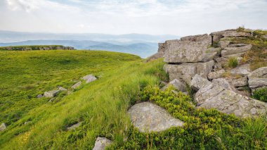 Çimenli yamaçtaki kayalar. Dağlık yaz manzarası. Mavi gökyüzündeki bulutlar