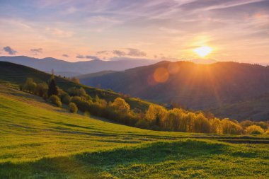 Kırsal bölgenin doğal güzelliği. Akşam ışığında çimenli yuvarlanan tepeler. Uzaktaki dağ sırtı