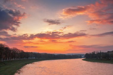 uzhhorod cityscape at dawn. linden alley on the embankment. gorgeous cloudscape above the river