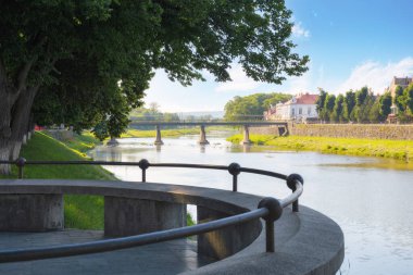Nehirli eski bir kasaba. Çiçekli ıhlamur ağaçlarıyla doludur. Köprü ve eski binalar sabah ışığında