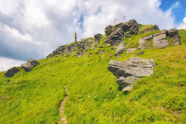 Pikui dağının dik yamaçlarında kayalık oluşumlar. Güneşli bir yaz gününde Ukraynalı Karpatların doğa manzarası. Kabarık bulutlu mavi gökyüzü