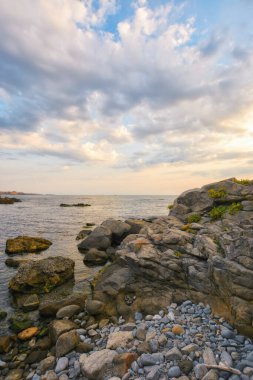 Gün doğumunda çakıl taşı sahili. Bulutlu bir sabahta deniz manzarası. Rahatla ve denizde dinlen.
