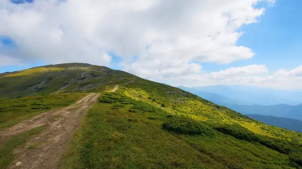 path uphill the petros mountain in summer. clouds on the blue sky above the summit. beauty of ukrainian alpine landscape