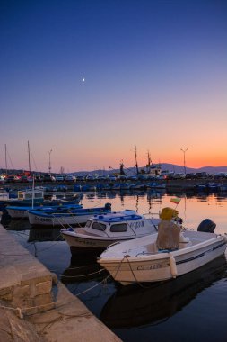 Sozopol, Bulgaria - 03 sep 2019: alacakaranlıkta limanda küçük balıkçı tekneleri. Bulutsuz gökyüzü suya yansıyor