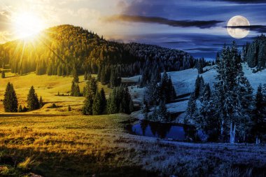 Sonbahar mevsiminde alacakaranlıkta güneş ve ay olan dağ manzarası. Tepenin eteğindeki vadide küçük bir gölet. Gündüz ve gece zaman kavramını değiştirir. Sabah ışığında gizemli ekinoks manzarası