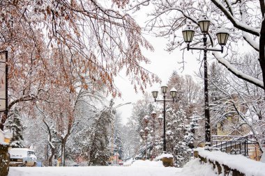 Kasabanın kışın sokakları. Yol kenarında karlı bir fener.