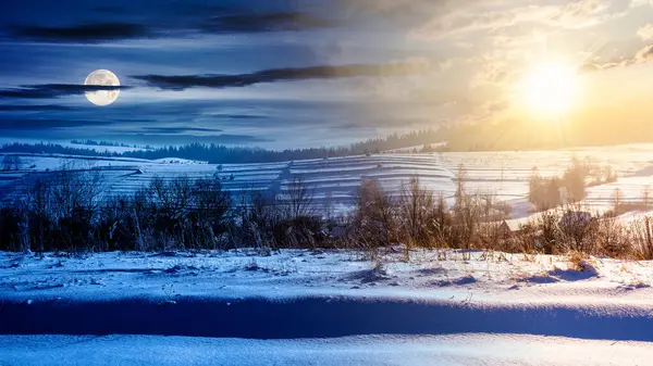 countryside landscape on a winter solstice day. rural scenery with snow covered rolling hills in the distance beneath a sky with sun and moon. day and night time change concept