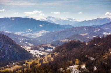 Baharın başında Carpathian kırsalının hareketli manzarası. Mart ayında Ukrayna 'nın dağlık kırsal arazisi. Yapraksız ormanlı tepeler. Dağlık dağlık dağlık tepelerde kar var. Uzakta runa
