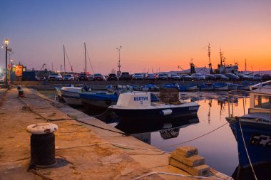 Sozopol, Bulgaria - 03 sep 2019: balıkçı tekneleri alacakaranlıkta limana demir attı. Sokak lambalarıyla aydınlatılmış manzara. Bulutsuz gökyüzü suya yansıyor