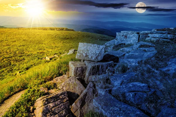 landscape with stones on the hillside with sun and moon at twilight. day and night time change on summer solstice concept. mysterious mountain scenery with green alpine meadows in morning light