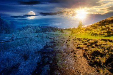 Bahar ekinoksunda Karpatya kırsal manzarası. Güneşli ve aylı bir gökyüzünün altındaki dağlık kırsal alan. Gündüz ve gece zaman kavramını değiştirir