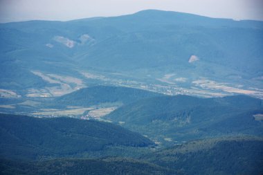 Yazın dağlık kayan bir manzara. Uzak vadideki köy. Sabah ışığında doğa arkaplanı