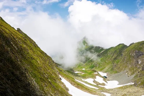 夏天的高山景观 在石山上的草地上 积雪点缀在乌云密布的天空之下 罗曼蒂亚山区受欢迎的旅游胜地 图库照片