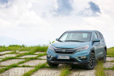 - Evet. Runa, Ukrayna - 22 Haziran 2019: Bulutlu bir günde dağlarda popüler aile cipi. Mavi renkli Honda CR-V 'nin dördüncü nesli. Asfaltlı platformda tüm tekerden çekişli araçlar. araba macera konsepti