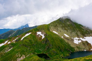 İbne sırtından Capra Buzulu Gölü, Romanya manzarası yukarıdan. Transilvanya Alpleri 'nin popüler seyahat yeri yazın. Bulutlu bir günde yüksek dağlı manzara. Aşırı hava turizmi