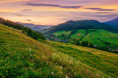 Şafak vakti çimenli tepeler arasındaki vadide bir köy. Transcarpathia, Ukrayna kırsal manzarası. Karpatya dağlarının üzerinde kızıl gökyüzü olan kırsal bölge. Volovets Bölgesi