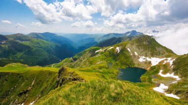Yazın Alp Gölü 'yle sakin bir manzara. Öğleden sonra Romanya 'nın güzel doğa manzarası. Transilvanya Alpleri 'nin cennet yeşili açık hava ortamı. Gökyüzünün altındaki uzak vadide kabarık bulutlar