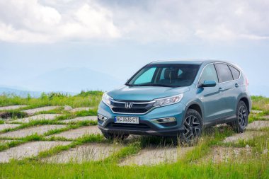 perechyn, transcarpathia, Ukrayna - 22 Haziran 2019: Çimenli bir tepenin üstüne park edilmiş aile cipi. Açık hava maceraları konsepti. Karpatya dağlarında yaz tatili. dramatik bulutlu hava