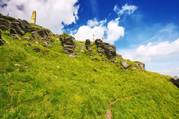 Pikui dağının dik yamaçlarında kayalık oluşumlar. Güneşli bir yaz gününde Ukraynalı Karpatların dağ manzarası. Kabarık bulutlu mavi gökyüzü