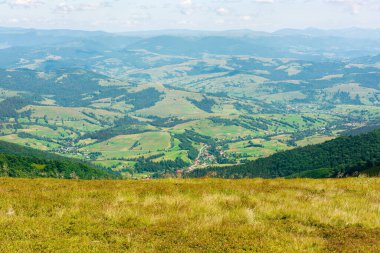 Pitpet köyünün uzak kırsal vadisine bakın. Dağlık kırsal alan. Yeşil çayırlar ve orman tepeleri. Karpatların güzel doğa manzarası