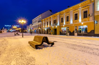 uzhhorod, ukraine - 06 jan 2019: winter cityscape at night. christmas illumination. street covered in snow. scene located near petofi square clipart