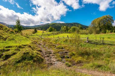 Dağlardaki kırsal alan. Güneşli bir sonbahar günü. Ukrayna 'nın Karpatya kırsalında. Samanlıkları ve ahşap çitleri olan bir manzara. Gökyüzünde kabarık bulutlar
