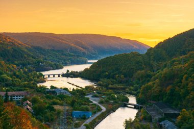 mountain river at dusk. landscape of romania in autumn. bridge over somes river in apuseni mountains in fall season. beautiful scenery of european countryside clipart