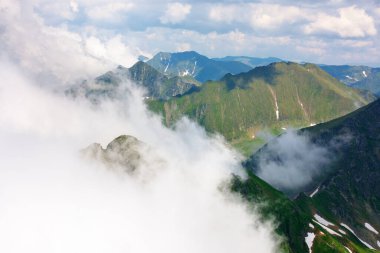 Dağlardaki bulutlar. dinamik bulutlar. Güneşli bir yaz gününde Transilvanya Alpleri manzarası. Çimenli ve karlı dik kayalık yamaçlı bir manzara. Güzel doğa geçmişi. resimimsi Romanya