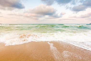 Dalgalar kumlu sahili yıkıyor. Seyahat yeri. Hava bulutlu. Akşamüstü Karadeniz manzarası. Avrupa 'nın inanılmaz iklimi 