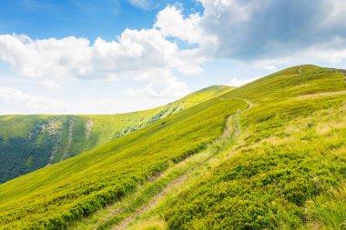 Yokuş yukarı giden bir dağ manzarası. Seyahat yeri. Yazın dik çimenli yamaçları olan güzel doğa manzarası. Dağın zirvesine giden yol. Gökyüzünde bulutlarla güneşli bir gün. tatil sezonu