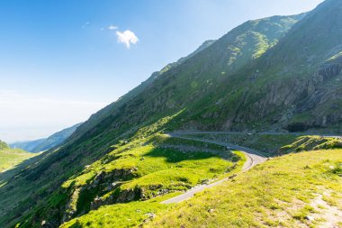 Transfagarasan yolu yokuş yukarı gidiyor. Alp Dağları 'ndan yükselen kıvrımlı bir dağ. Romanya 'nın dağlık arazisinde bir seyahat rotası. Yazın güneşli bir gün. Vadinin manzarası. Güney Karpatya Yılanı