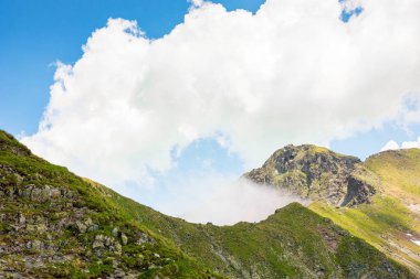 Yazın İbne Dağları manzarası. Romanya 'nın güzel doğa manzarası. Dik yamaçlar, çimenli yamaçlar ve güneşli bir günde mavi gökyüzünde bulutlar olan kayalık tepeler. manzaralı seyahat arkaplanı