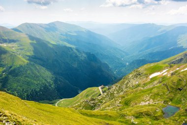 Yazın Romanya 'nın dağ manzarası. Tatil sezonu. Alp gölü olan güzel bir açık hava manzarası. Manzaralı vadi manzarası. Mavi gökyüzü ve bulutlarla seyahat. çimenli yamaç