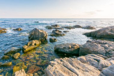 Karadeniz 'de güzel bir gün doğumu. Geniş ufukta. Sabah ışığında mavi gökyüzünde kayalık sahil ve bulutlar. Yaz tatilleri ve hava değişimi konsepti. tatil sezonu