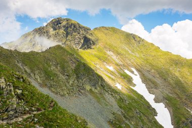 Yazın İbne Dağları manzarası. Romanya 'nın güzel doğa manzarası. Dik yamaçlar, çimenli yamaçlar ve güneşli bir günde mavi gökyüzünde bulutlar olan kayalık tepeler. manzaralı seyahat arkaplanı
