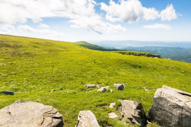 Güneşli bir sabahta alp çayır manzarası. Karpat Dağları 'nın yeşil tepelerindeki kayalar. Mavi gökyüzündeki bulutlar