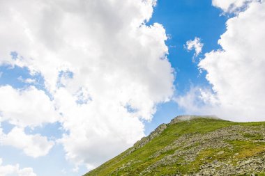 Dağlı manzara ve bulutlu mavi gökyüzü. Manzaralı. Taşlar ve otlarla dolu dik bir tepe. Yazın Romanya 'nın güzel doğası