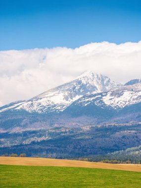 Baharda Tatra Dağı manzarası. Seyahat için Avrupa 'nın doğal manzarası. Zirvesinde kar olan Slovakya kırsal manzarası. Mavi gökyüzü ve turizm için bulutlu güzel dağ manzarası